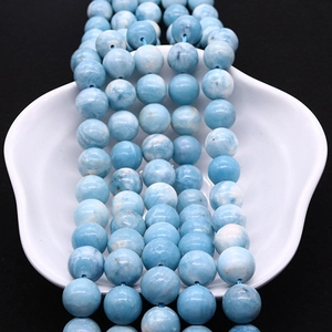 Natural larimar beads with blue water patterns in a shell plate on black background