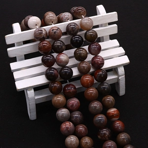 Natural petrified wood beads on a white wooden bench against a black background