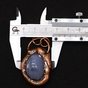 Detailed view of striped agate pendant being measured with calipers on black background
