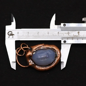 Macro view of natural striped agate pendant with irregular bronze base and size measurement