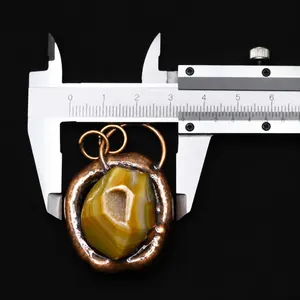 Macro shot of irregular natural agate pendant being measured with calipers for size accuracy