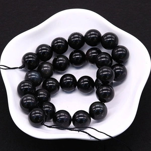 Natürliche Obsidianperlen für DIY-Schmuck auf einer weißen Porzellanschale