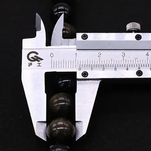 Macro d'une perle d'obsidienne dorée de 12 mm mesurée avec un pied à coulisse en métal