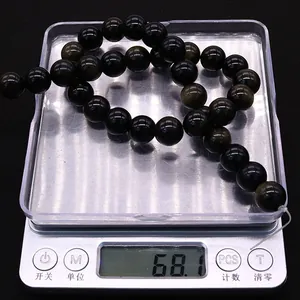 Détail macro de perles d'obsidienne noire naturelle sur balance pesant 68,1 grammes