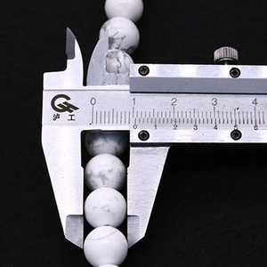 Detail showing 8.5mm white turquoise bead diameter measurement with a caliper