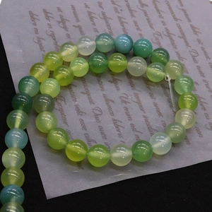 Polished natural green agate round beads on translucent paper for DIY necklace jewelry