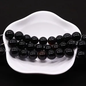 Polished natural black striped agate beads for DIY jewelry making on white ceramic plate