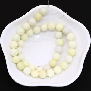 Natural ivory jade round beads in a white floral bowl for DIY jewelry making