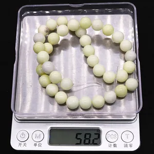 Macro shot of natural ivory jade round beads being weighed on a scale for DIY jewelry