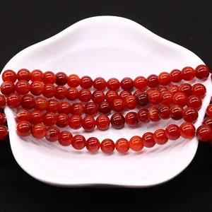 Polished red dragon vein agate round beads for DIY jewelry making on white petal tray
