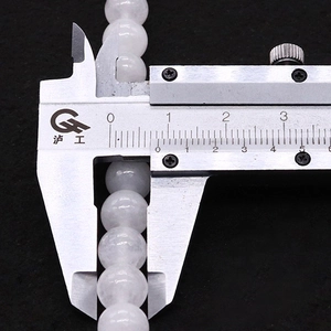 Detailed measurement of 8.5mm white gemstone beads showing precise diameter with a caliper