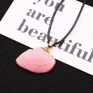 Detail view of pink sea shell pendant with gold electroplated edge on black background