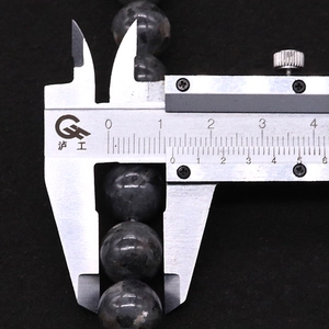 Macro shot measuring 10mm diameter of grey labradorite gemstone beads with a caliper