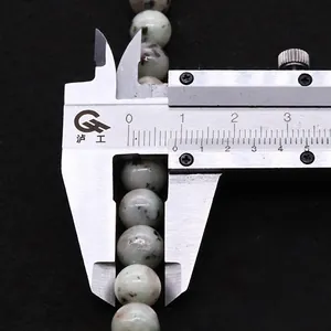 Macro-opname van 10mm natuursteen kralen gemeten met een metalen schuifmaat voor sieraden