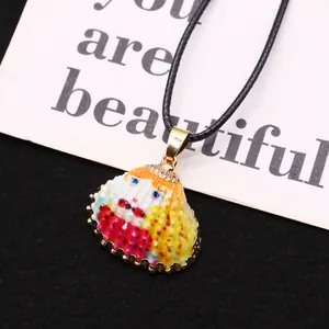 Détail macro d'un pendentif coquillage peint à la main avec bords dorés sur cordon noir