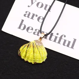 Détail du pendentif coquillage jaune avec bordure dorée sur une carte de présentation