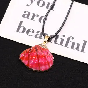 Détail d'un pendentif en coquillage rose avec bordure dorée sur fond de velours noir chic