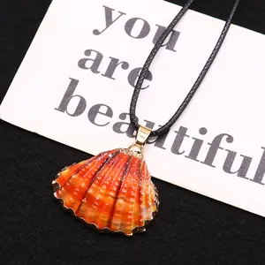 Détail du pendentif coquille Saint-Jacques naturelle aux bords dorés et cordon noir