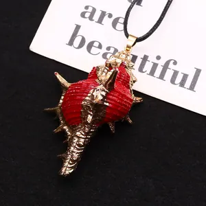Primer plano de colgante de caracola roja con borde dorado sobre fondo negro texturizado