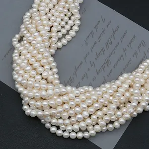 Natural freshwater pearl beads in milky white arranged in S-curve on dark background