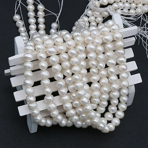 Natural freshwater pearl strands displayed on white wooden fence over black leather