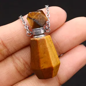 Makroaufnahme von Tigerauge-Stein-Aroma-Anhänger zwischen Fingern mit Metallkette