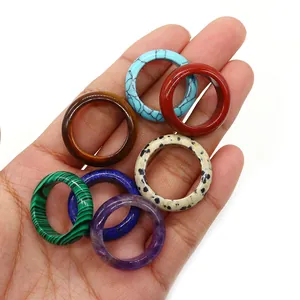 Polished natural crystal and agate stone rings in various colors held on a palm