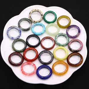 Variety of polished natural stone rings including malachite and agate in a floral tray