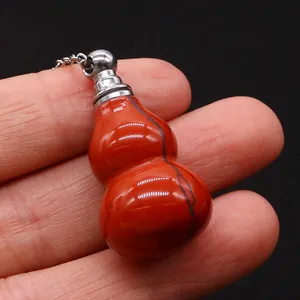 Red jasper gourd perfume bottle pendant with silver chain shown in hand on black background