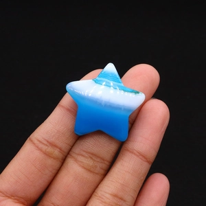 Macro view of a star-shaped blue dalmatian stone bead held by hand for jewelry DIY