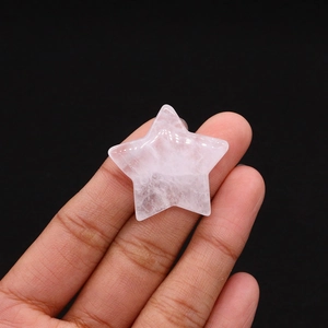 Macro view of a small star-shaped rose quartz crystal stone held by a hand