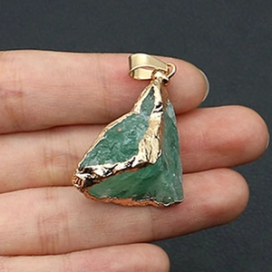 Detail van een onregelmatige groene natuurlijke kristallen hanger met vergulde rand