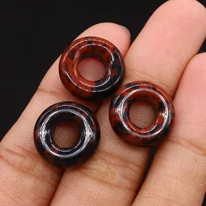 Drei polierte Mahagoni-Obsidian-Donut-Perlen auf der Fingerspitze für DIY-Schmuckzubehör