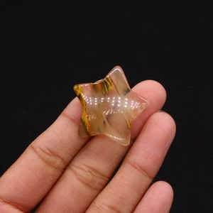 Detailed macro shot of star-shaped polished natural stone bead held between fingertips