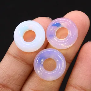 Makro-Detail von drei Opal-Donut-Perlen auf Fingern für DIY-Schmuckherstellung