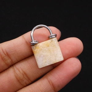 Macro shot of square natural stone pendant with warm mineral textures and silver metal loop
