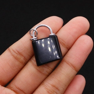 Miniature black obsidian lock pendant held between fingers showing its small size