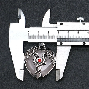 Detail of heart-shaped stone pendant with silver wings and a red crystal inlay