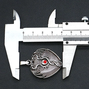 Detail view of heart-shaped stone pendant with silver vine wrap being measured by caliper