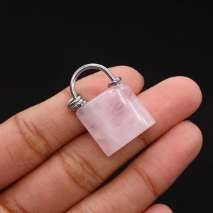 Natural rose quartz concentric lock pendant with silver handle on a black background