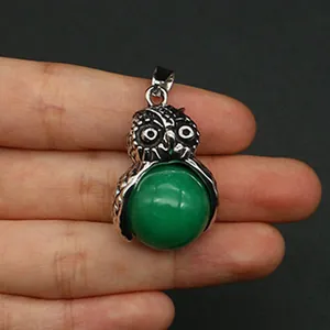 Dettaglio ravvicinato di un ciondolo a forma di gufo con pietra preziosa verde