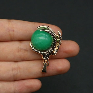 Detail of a gold-plated dragon claw pendant holding a green stone sphere in hand