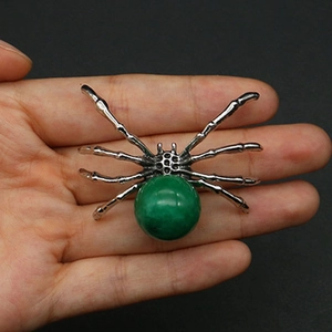 Detailed macro view of spider-shaped natural stone pendant with green gem and silver legs