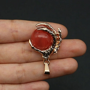 Detail view of golden dragon claw pendant holding a red stone ball with scale textures