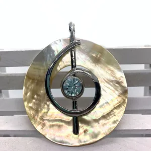 Macro shot of seashell pendant featuring silver treble clef and blue crystal gem detail