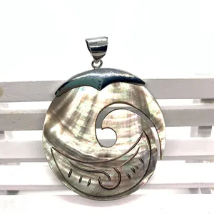 Close-up of black mother-of-pearl shell pendant with wave hollow carving and silver bail
