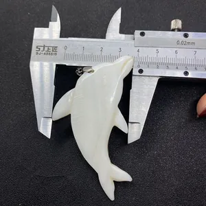 Macro view of 40mm dolphin-shaped natural shell pendant measured with a caliper tool