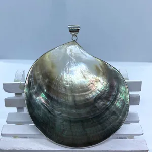 Macro detail of round black shell pendant with iridescent luster and silver bail