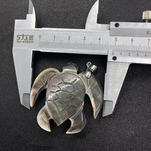 Macro shot of a dark shell sea turtle pendant being measured with a metal caliper