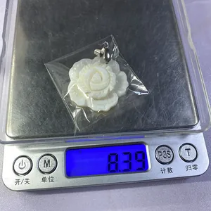 Vue détaillée d'un pendentif fleur de pivoine en nacre pesant 8,39g sur une balance